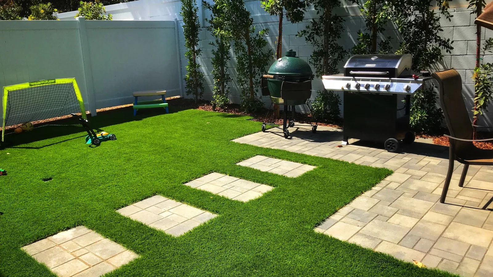 Artificial turf installation in a backyard with square stepping stones set into the turf