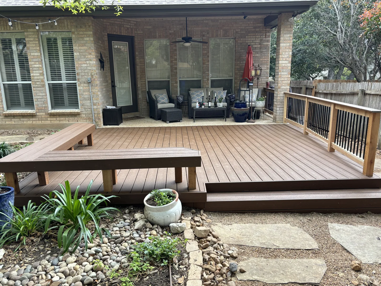 Composite deck with built-in benches and a railing behind a brick home
