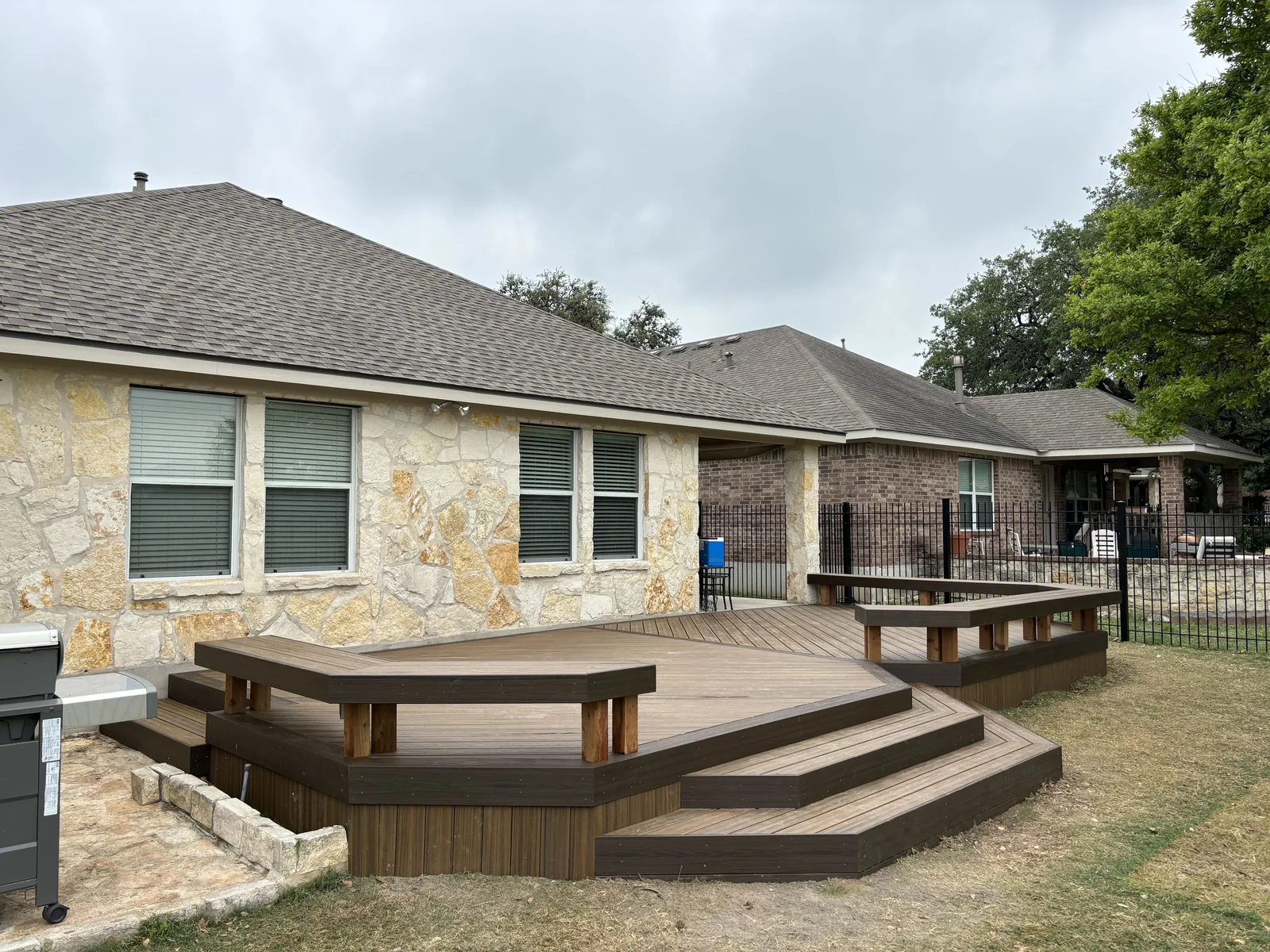 Composite deck with built-in benches and wide steps beside a stone home