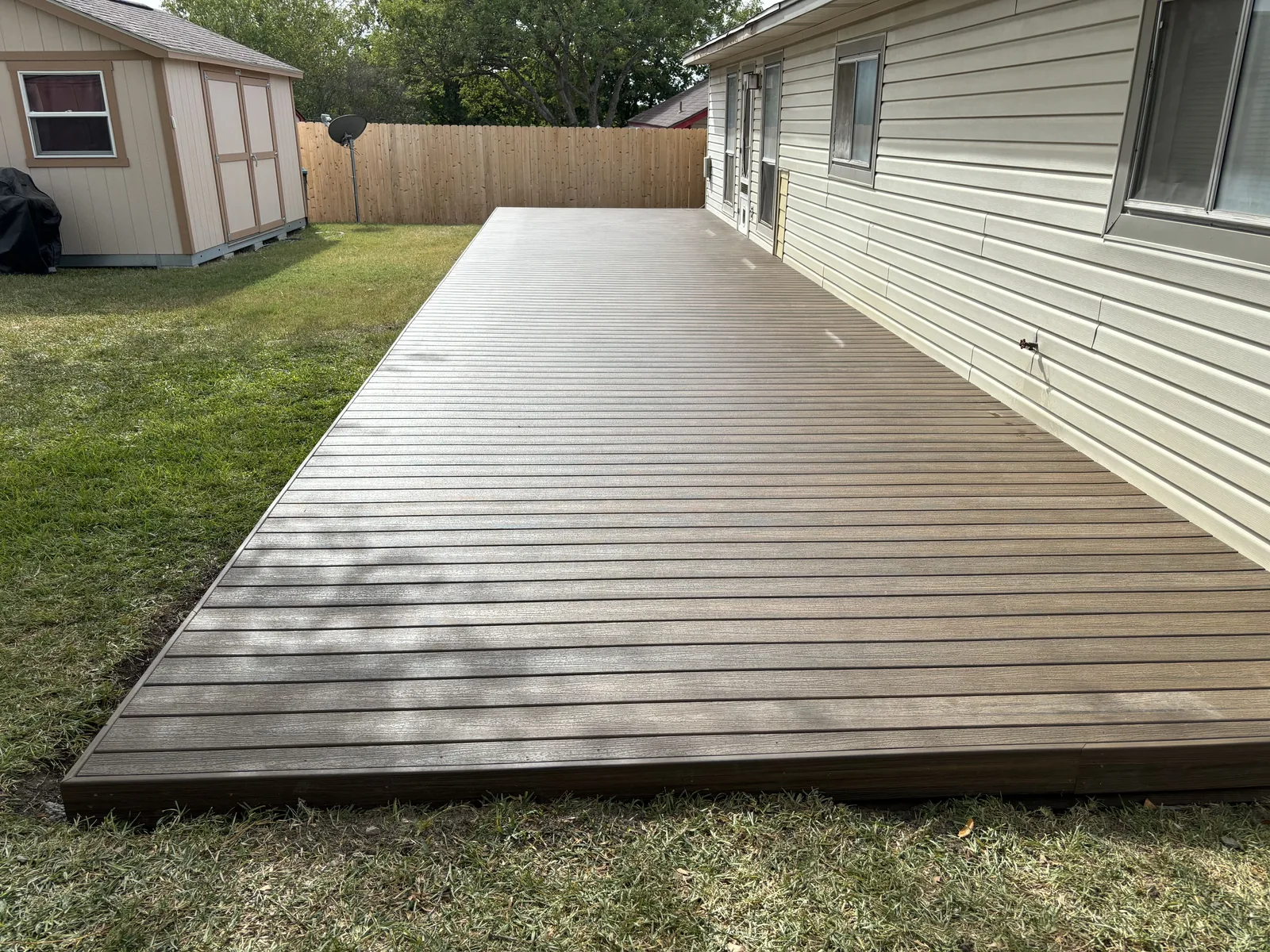 Low composite deck running the length of a house, built close to the lawn