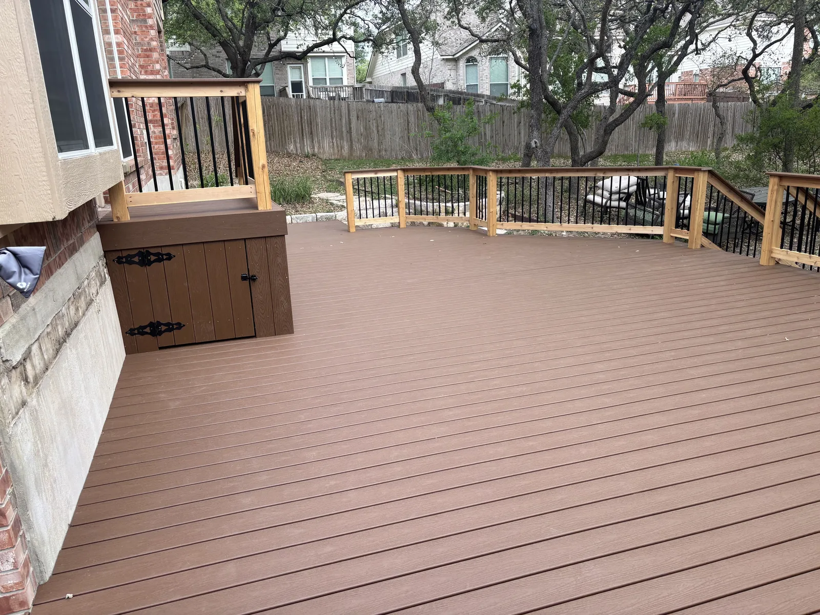 Composite deck with a railing and a skirted storage door at the house