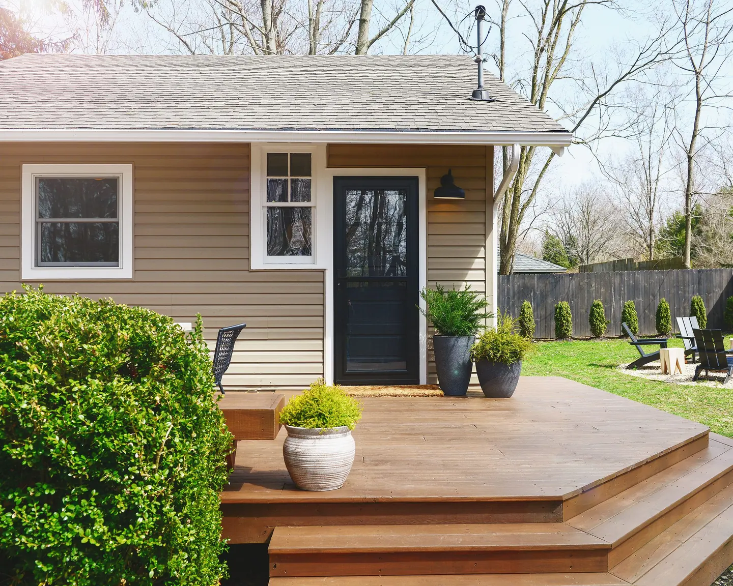 Stained wood deck and wide steps outside a small tan house